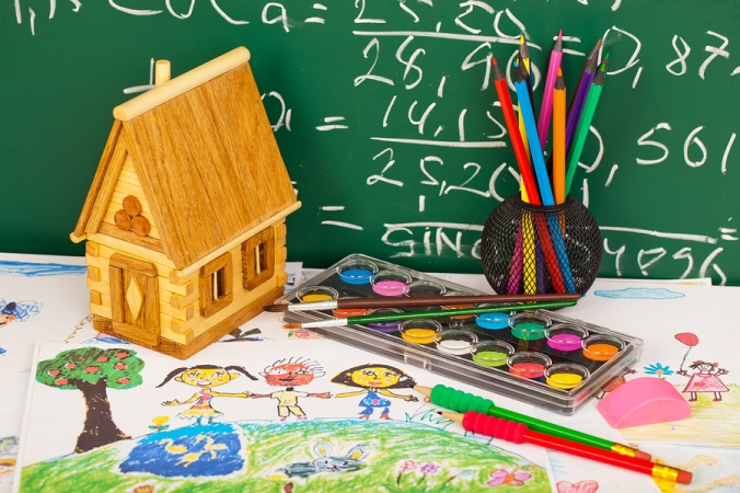 School supplies for teaching primary school students on a table in front of a chalkboard